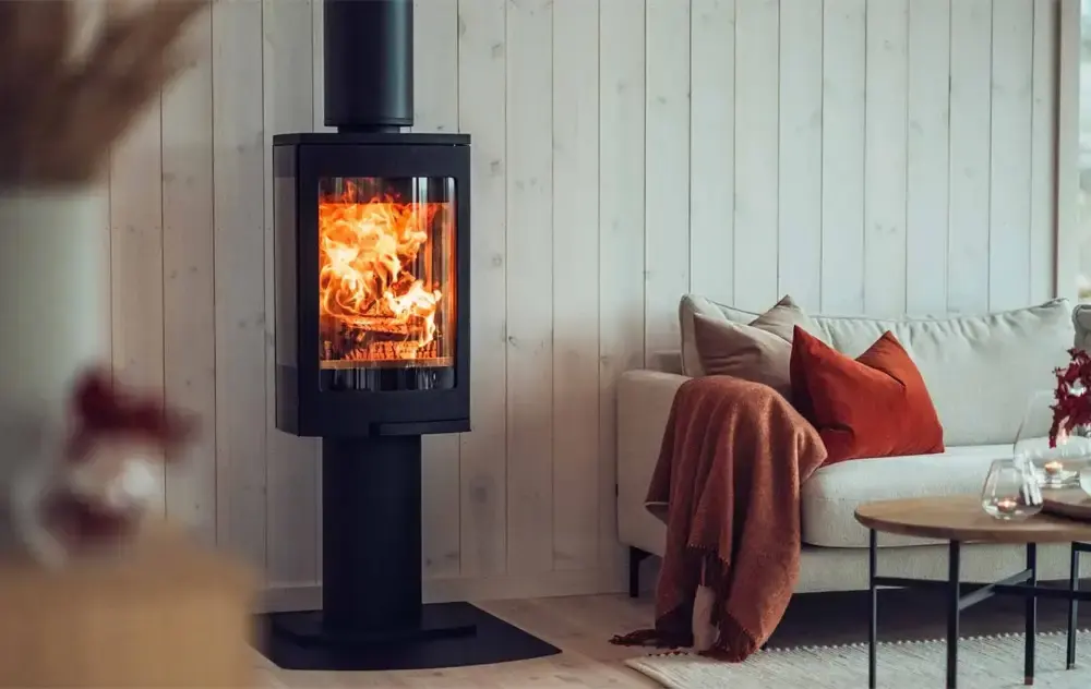 Svart peisovn med stor glassdør og synlig ild i stue